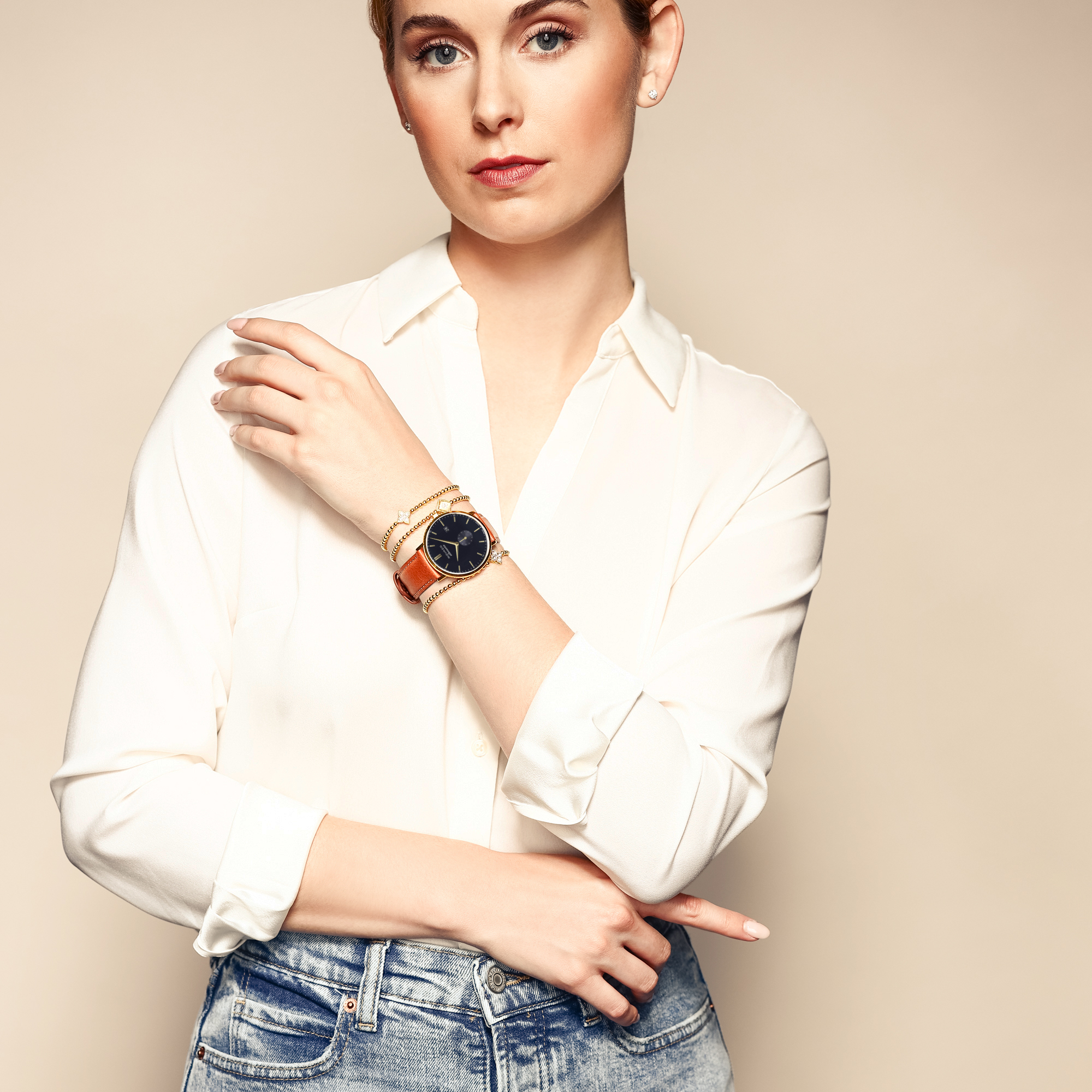 Female model wearing yellow gold beaded bracelets styled with a watch